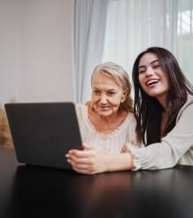 Home Care assistance by A Plus Homecare employee to an older lady with her laptop