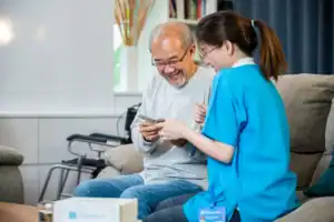 Home health nurse helping an elderly man manage his medication at home.