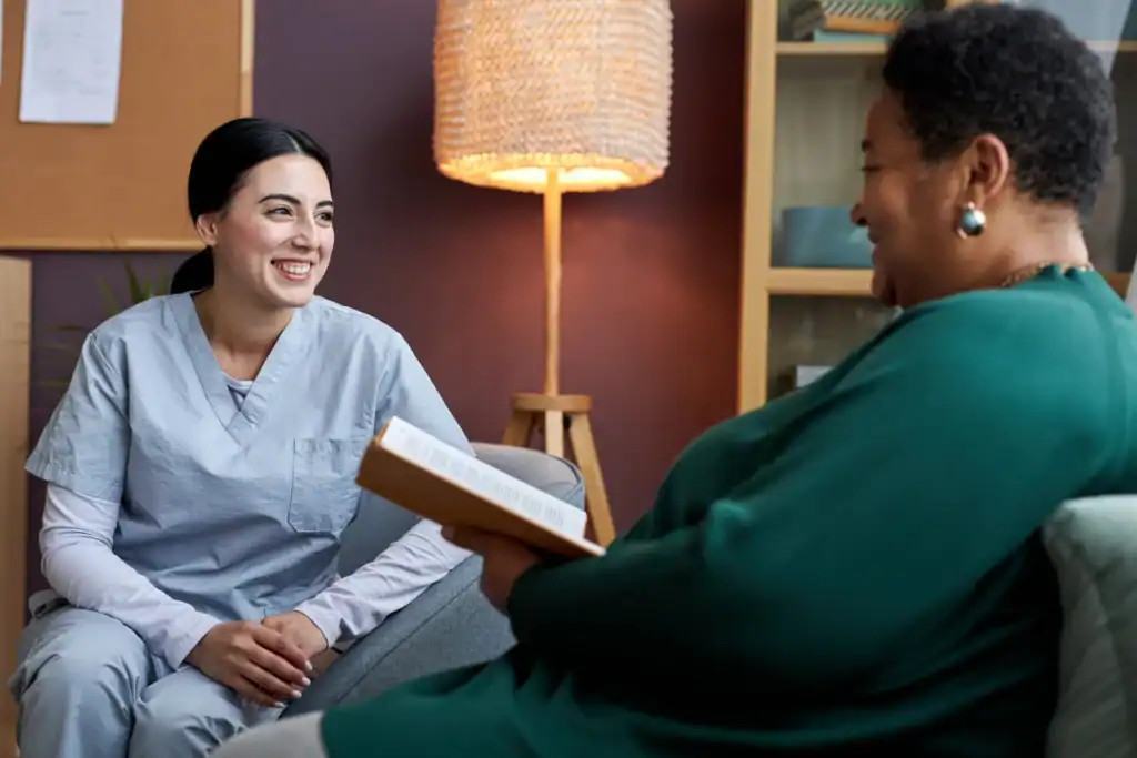 Happy caregiver and senior woman discussing home healthcare options.