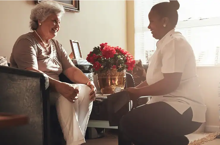 Elderly woman and caregiver sharing a warm moment with red flowers on table