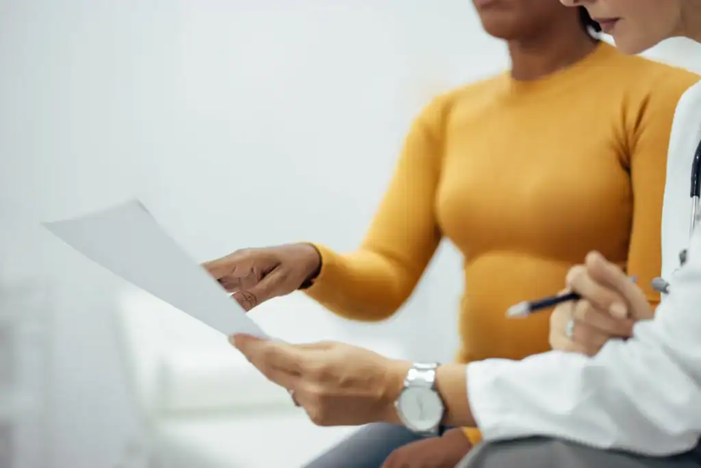 Doctor reviewing Medicaid waiver paperwork with a patient during consultation.
