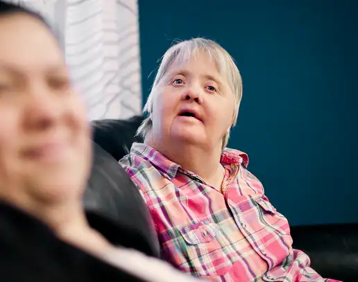 Woman with Down syndrome wearing a plaid shirt. Home care support.
