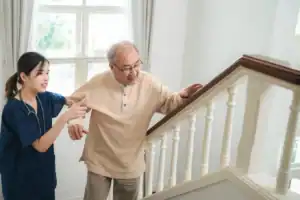 Nurse assisting elderly man on stairs, home safety modifications